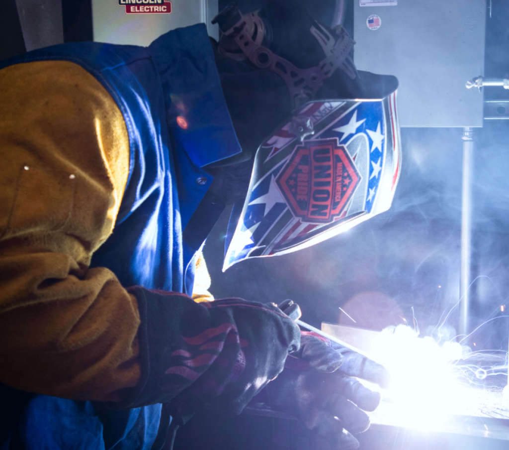 Welder in protective gear working with bright sparks, showcasing union pride and skilled craftsmanship.